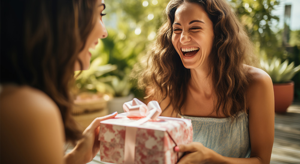 Nasmiješena žena daje prijateljici dar.