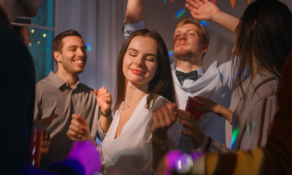 Grupa ljudi koja pleše na zabavi, među kojima je žena koja uživa u glazbi.