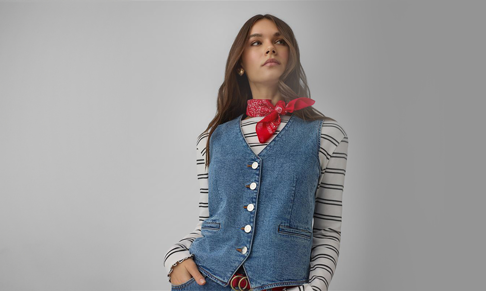 Žena nosi plavi traper prsluk i crvenu bandanu oko vrata.