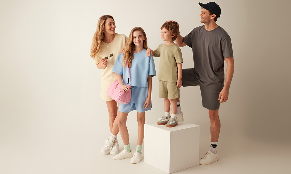 Obitelj u pastelnim odjevnim kombinacijama pozira zajedno na svijetloj pozadini.